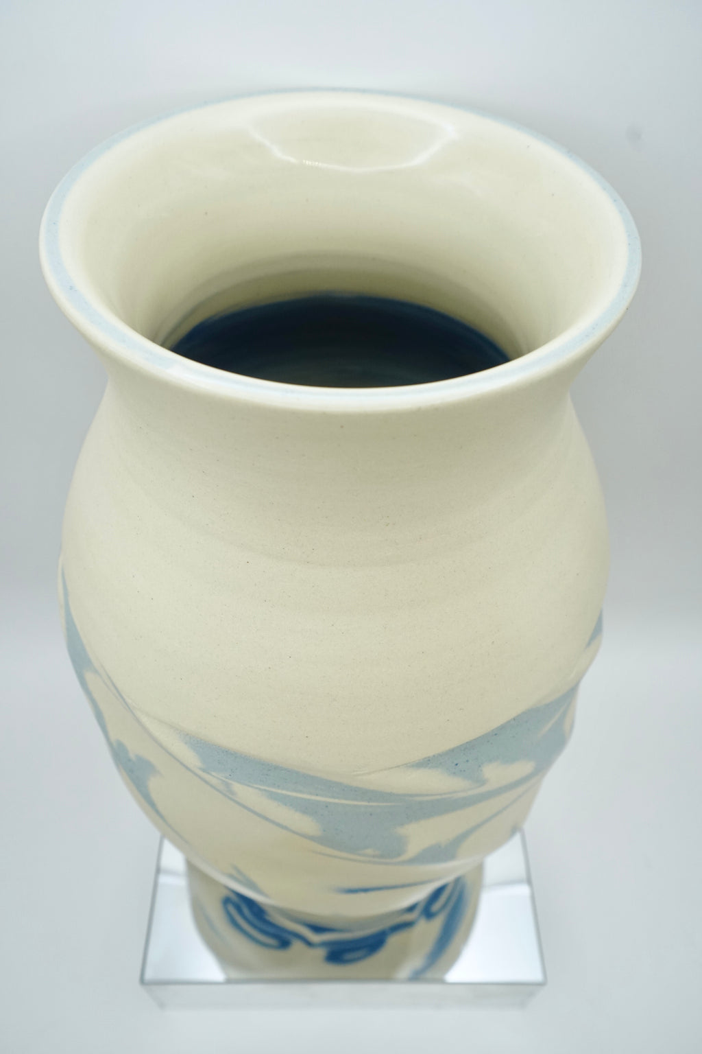 White ceramic vase with blue patterns on a reflective surface and white background