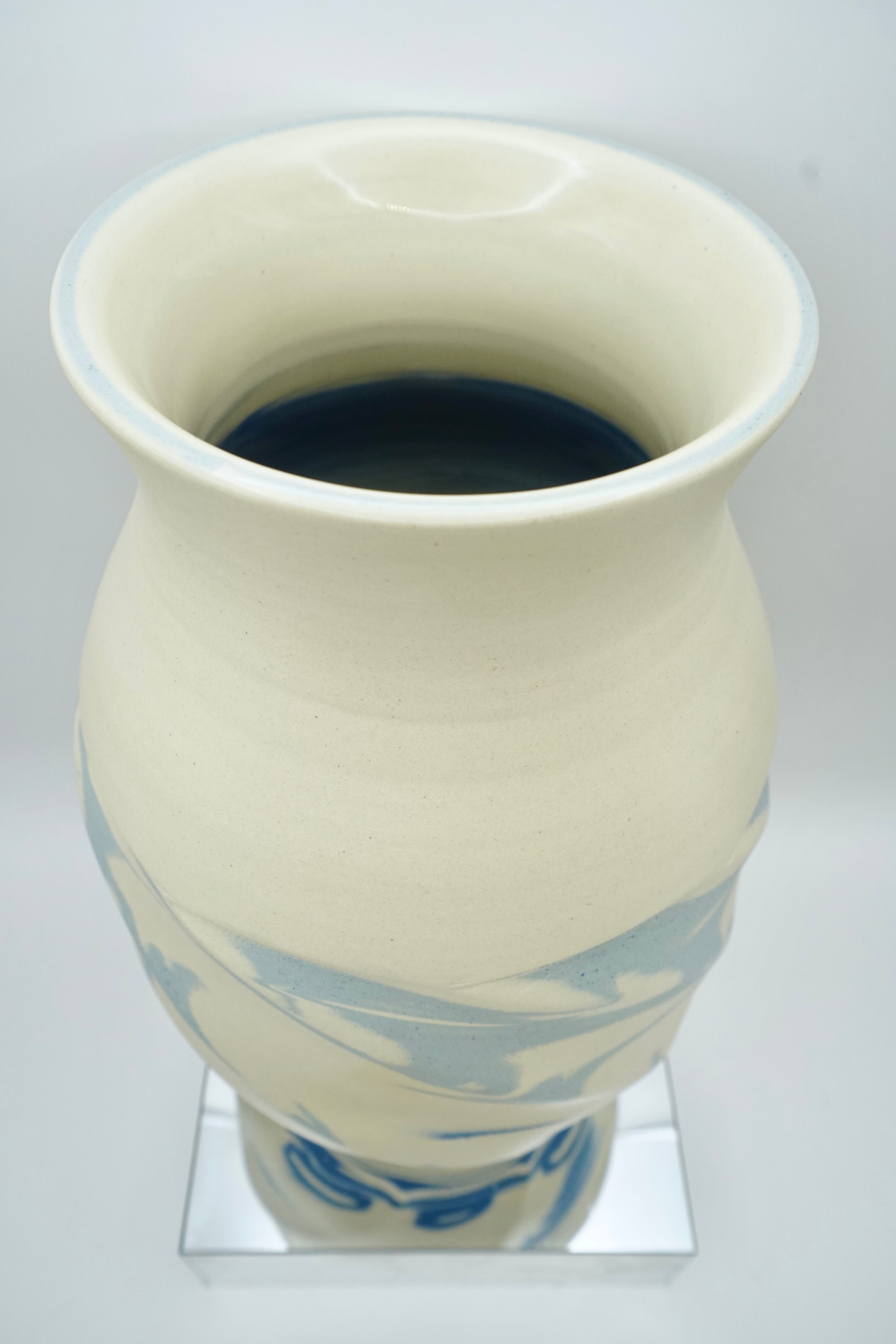 White ceramic vase with blue patterns on a reflective surface and white background
