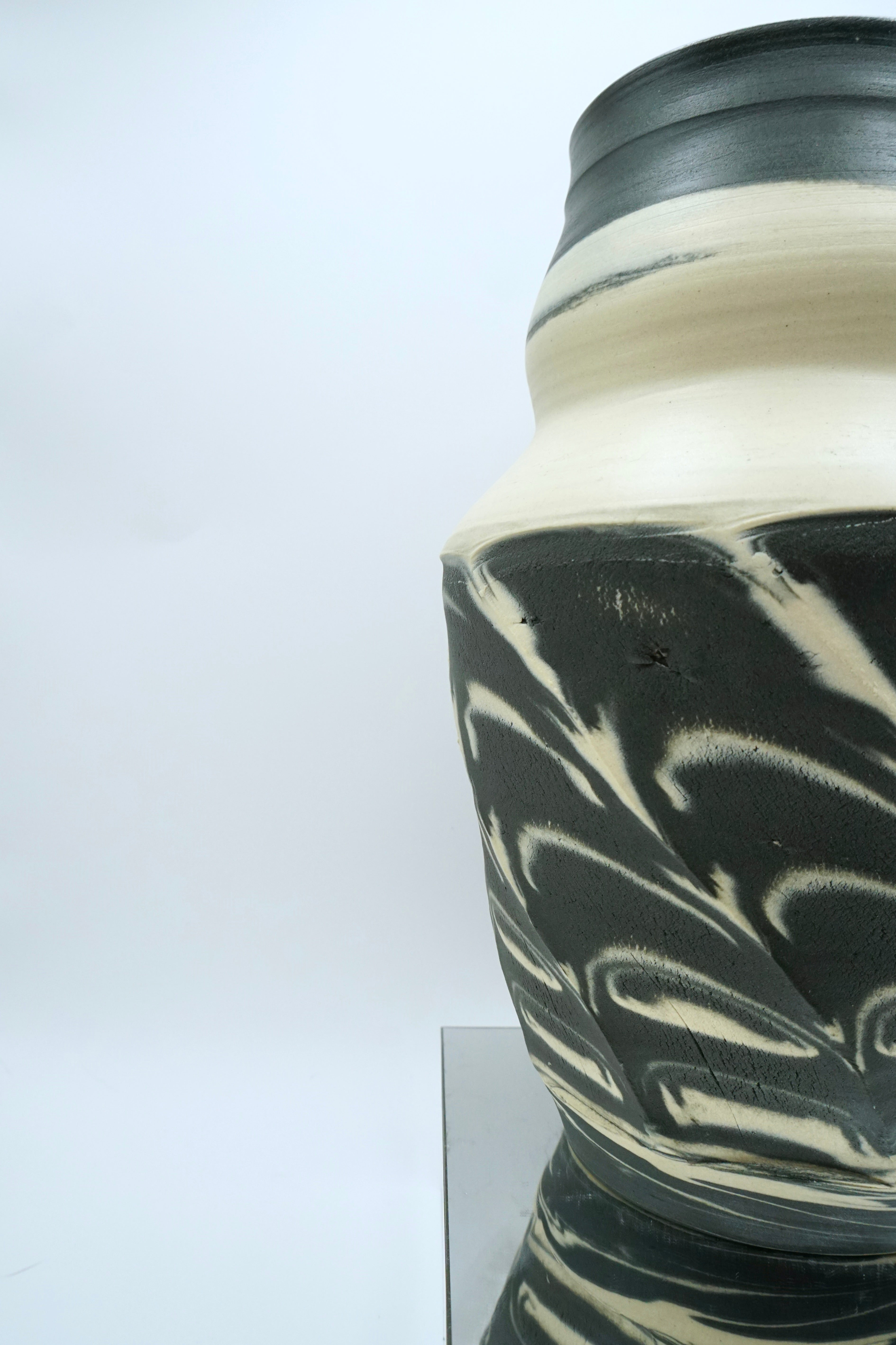 Black and white ceramic vase on a reflective surface and white background