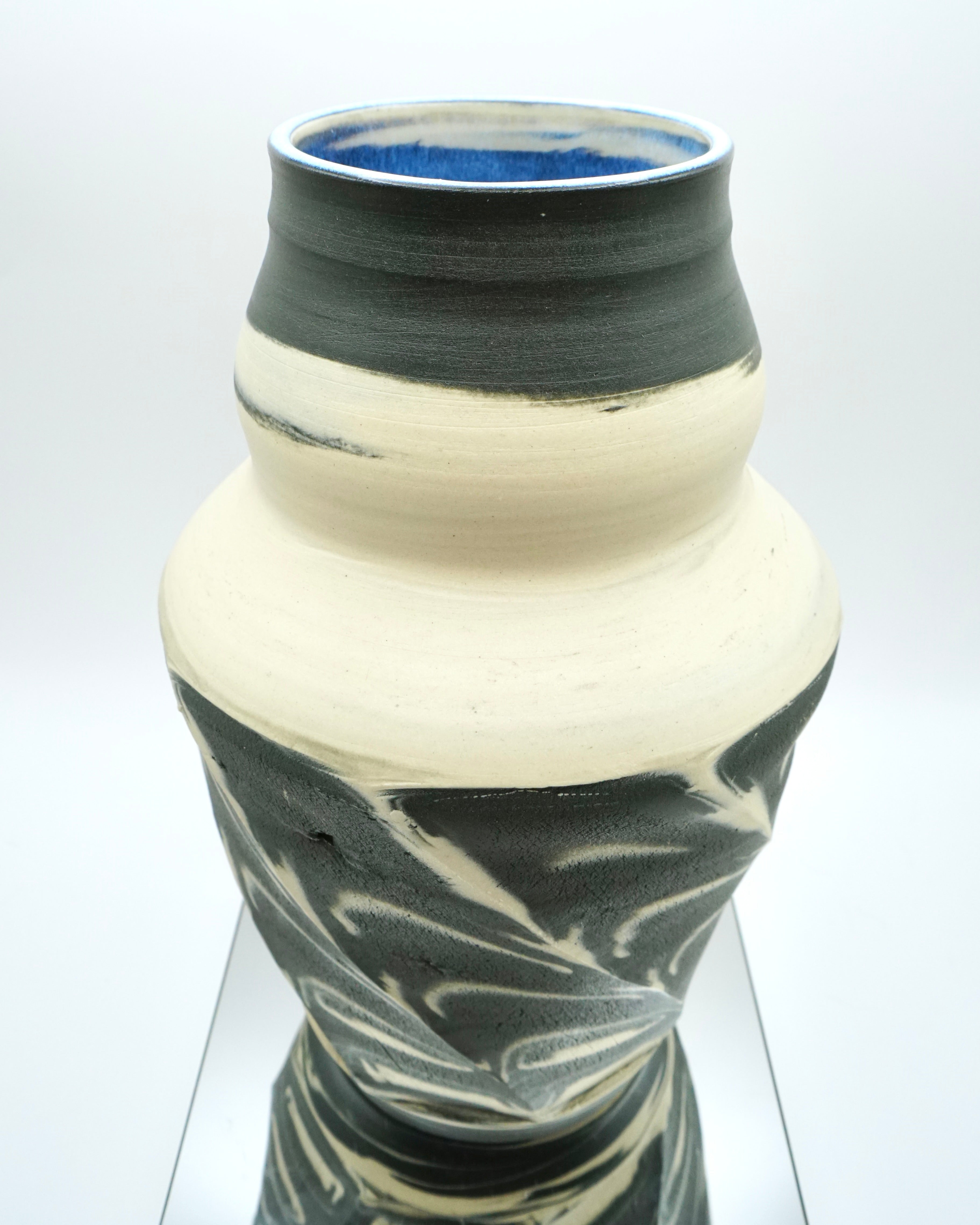 Ceramic vase with black and white marbled design on a reflective surface and white background