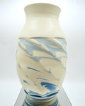 Ceramic vase with blue and white abstract pattern on a reflective surface and white background